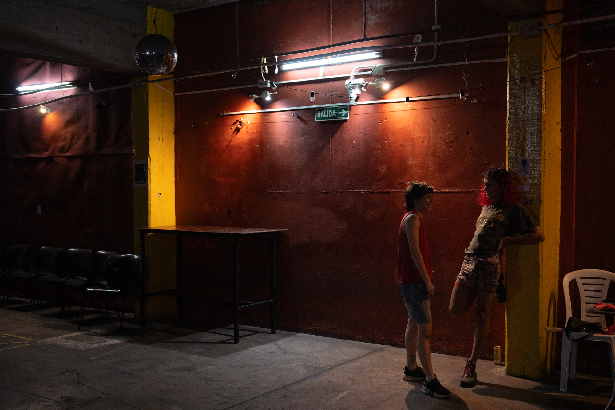 Dos personas se conversan en una sala vacía y oscura. 