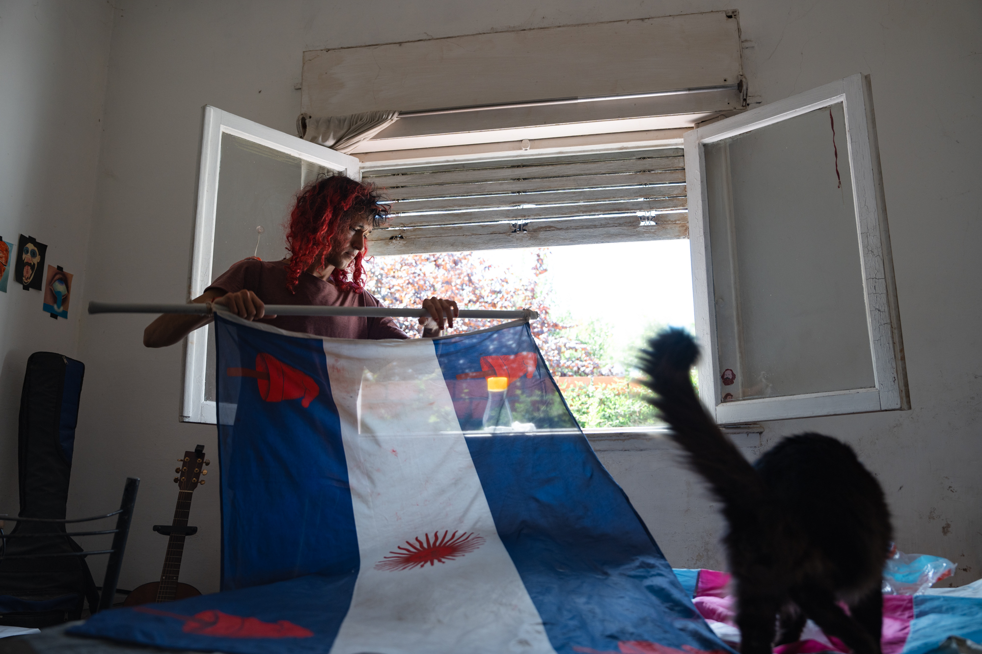 Una mujer levanta una bandera de la cama, mientras que un gato camina por el frente.
